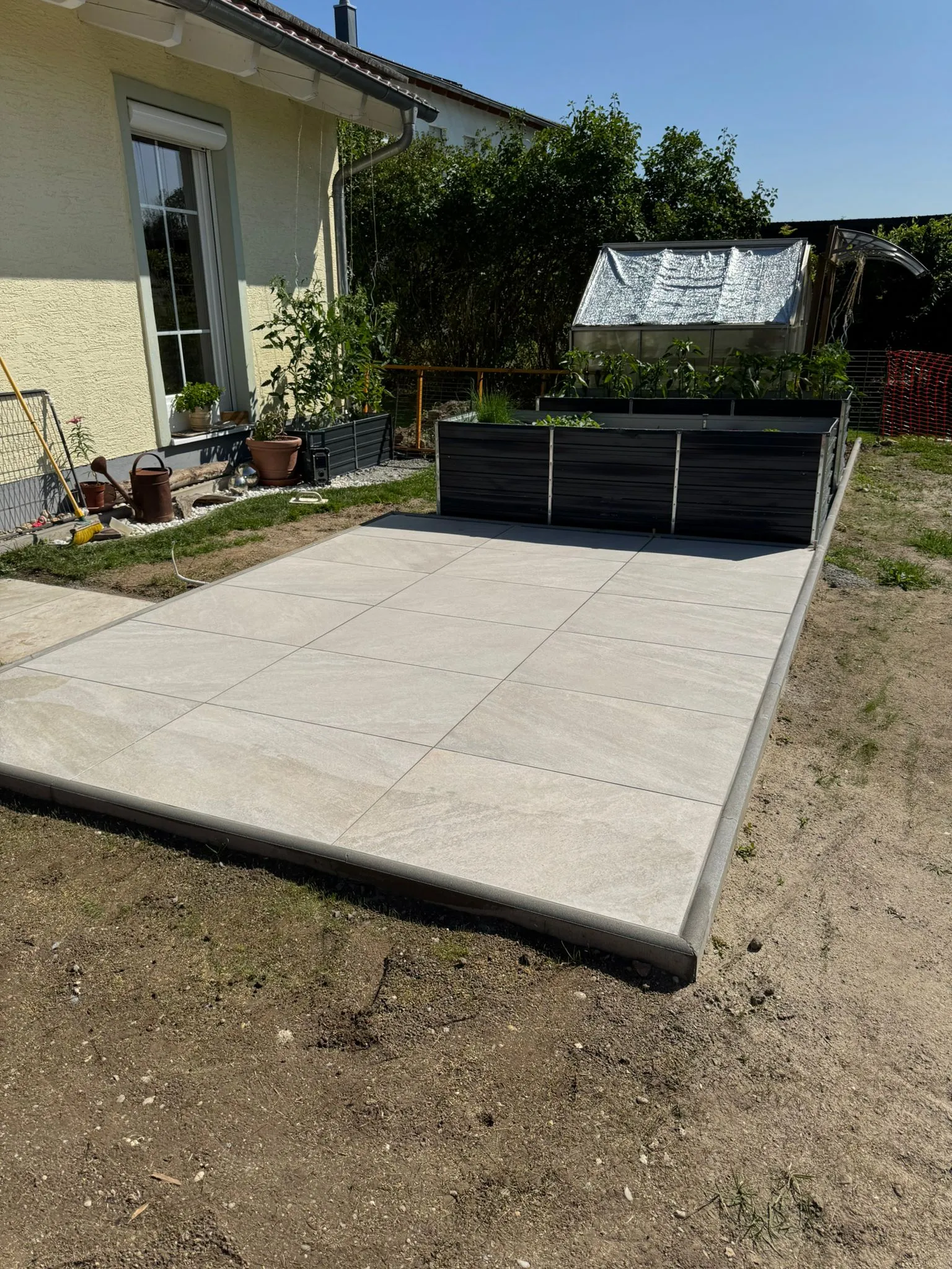 Neu gepflasterte Terrasse mit Hochbeeten